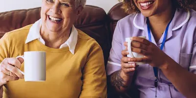 Social Care Worker conversing with two older ladies.
